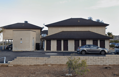 A car is parked in front of a building with a black roof.