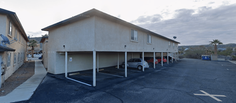 A parking lot with a building and cars parked.