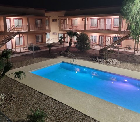A swimming pool in front of a building at night.