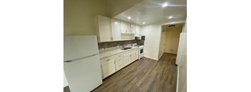 A kitchen with white appliances and wooden floors.
