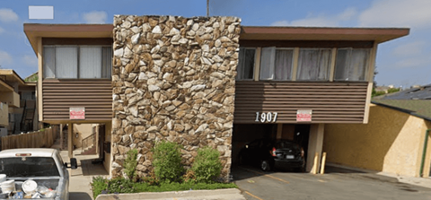 A house with a stone wall and the number 1907 on it.