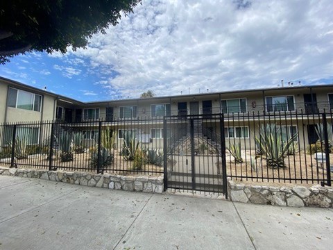 A black metal fence surrounds a building with a stone base.