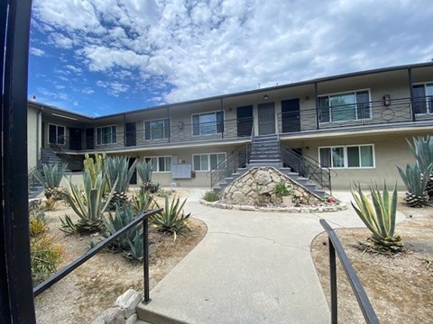 A concrete walkway leads to a building with a stone staircase.