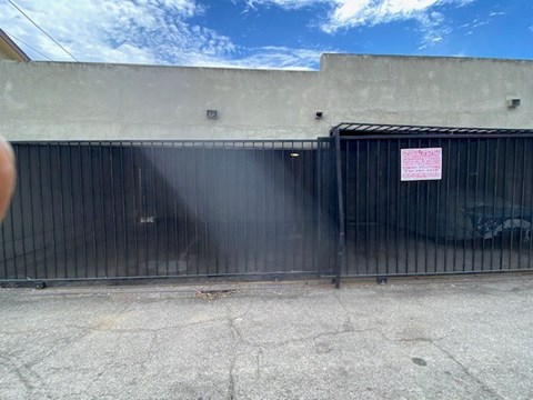 A black gate with a pink sign on it.