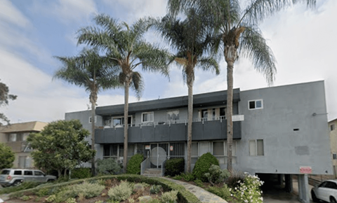 A grey building with palm trees in front.