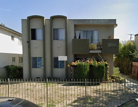 A three-story building with a balcony and a fence in front.
