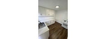 A kitchen with white cabinets and a wooden floor.