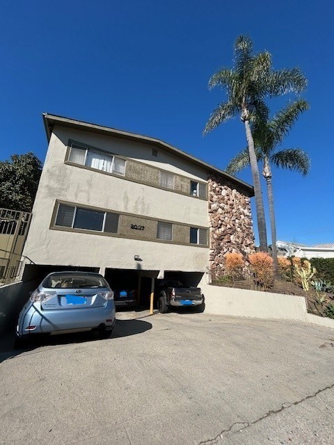 A car is parked in front of a building with a palm tree in the background.