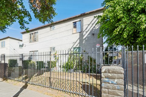 A white building with a black fence in front.