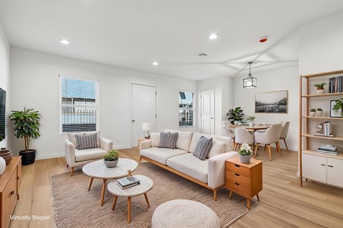 A living room with a white sofa, a coffee table, and a large window.