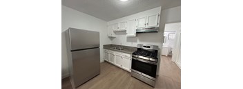 A kitchen with a stainless steel refrigerator, stove, and cabinets.