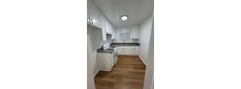 A kitchen with white cabinets and a stove top oven.