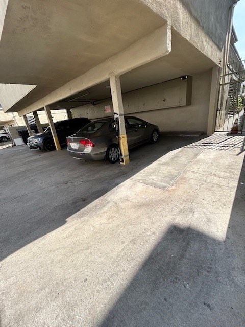 A concrete parking garage with cars parked under a roof.