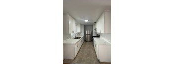 A kitchen with white cabinets and a marble countertop.