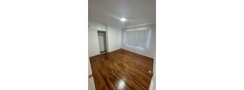 A room with wooden flooring and a window with blinds.
