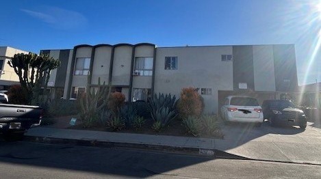 A white car is parked in front of a grey building.