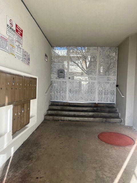 A hallway with a red mat on the floor and a metal gate in the background.