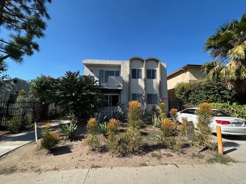 A modern house with a white fence and a car parked in front.