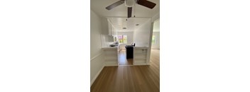 A room with a ceiling fan and wooden floors.