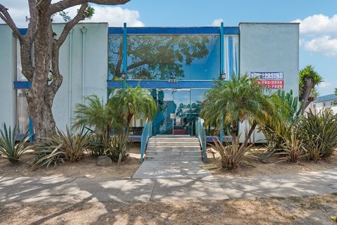 A blue building with a glass window and a red sign on it.