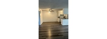 A room with a kitchen area and a ceiling fan.