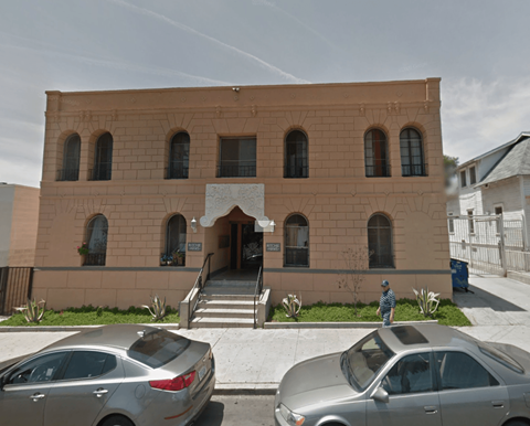 A tan building with a man standing in front of it.