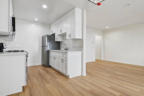 A kitchen with white cabinets and a wooden floor.
