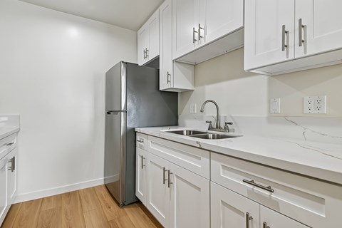 A kitchen with white cabinets and a stainless steel refrigerator.