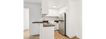 A kitchen with white cabinets and a black counter top.