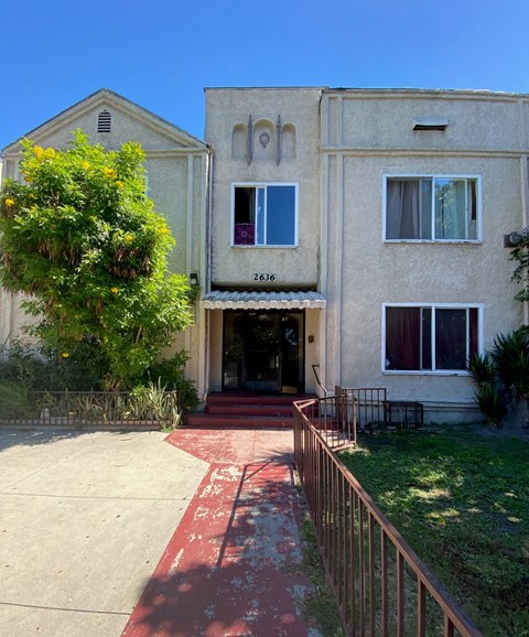 A two-story building with a red door and a balcony on the second floor.