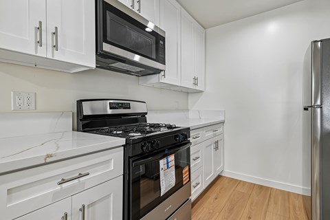 A kitchen with white cabinets and a black stove top oven.