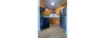 A kitchen with wooden cabinets and a black dishwasher.