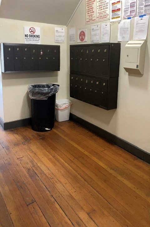 A room with a black trash can and a no smoking sign.