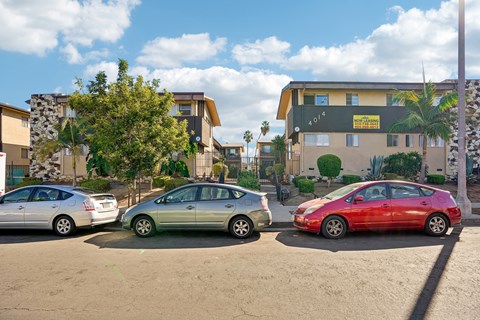 Three cars parked in a lot with a building in the background.