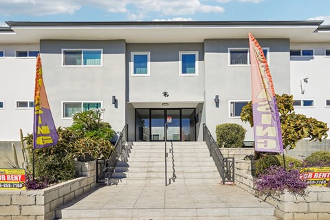 A building with a grey facade and a staircase leading to the entrance.