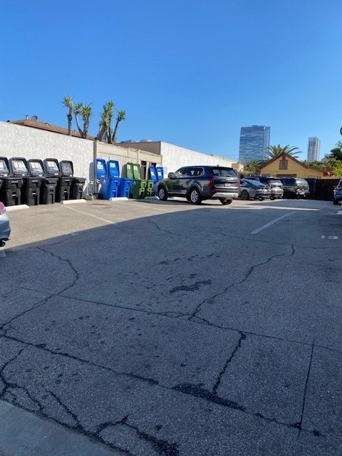 A parking lot with a white car and a blue car parked in front of a building.