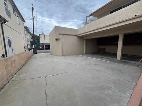 A parking garage with a concrete floor and a building on the right side.