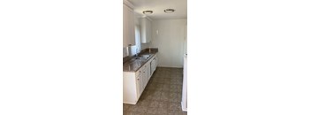 A kitchen with white cabinets and a tiled floor.