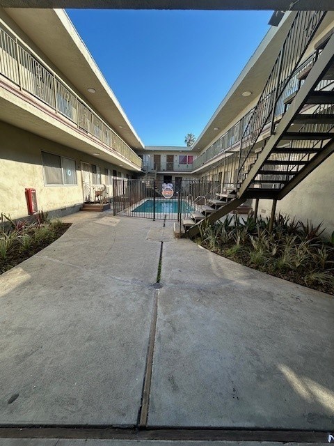 A concrete walkway leads to a pool area in a residential complex.