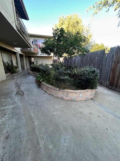 A concrete patio with a small tree and bushes in a circular planter.