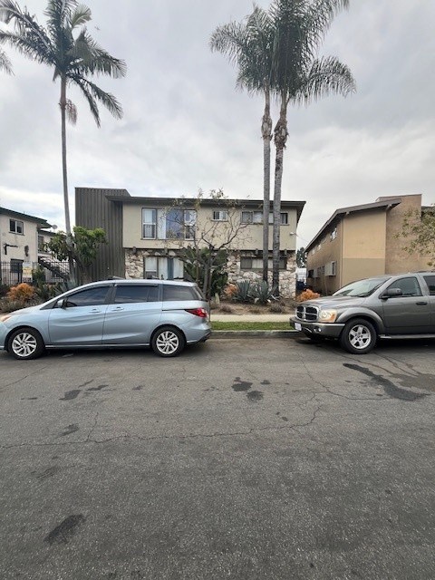 Two cars parked in a driveway with a house and palm trees in the background.
