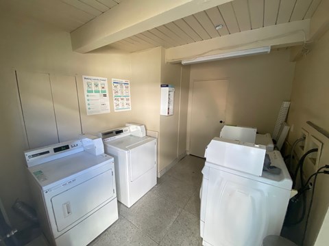 A laundry room with a washer, dryer, and ironing board.