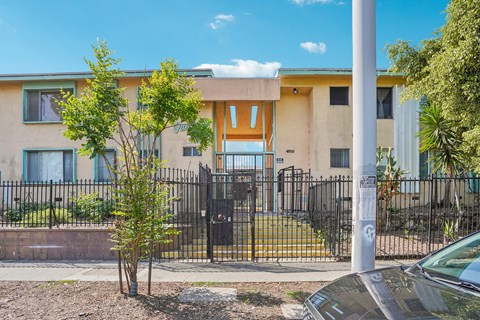 A building with a black fence and a tree in front of it.