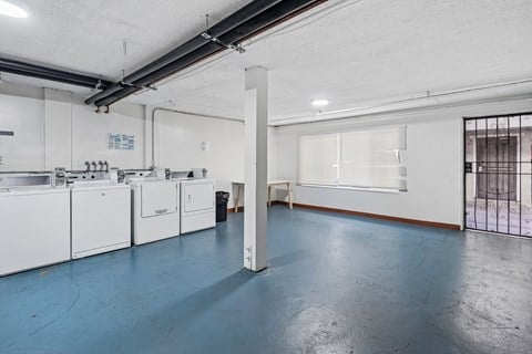 A large, empty room with a blue floor and white walls.