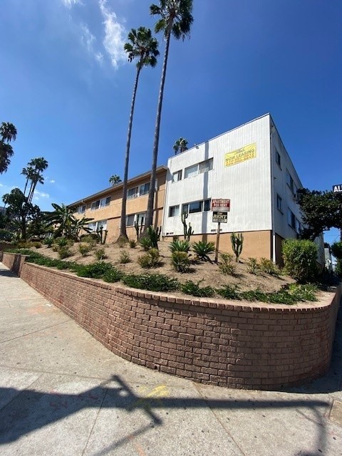 A building with a yellow sign on it and a brick wall in front.