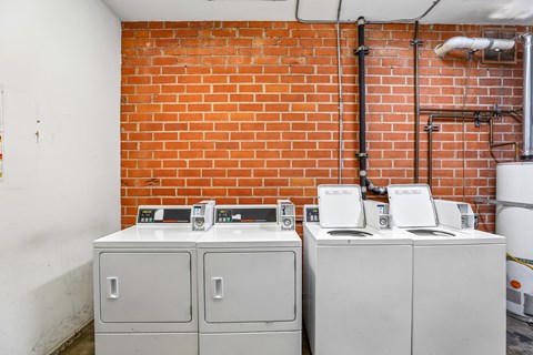 Three white electrical boxes are on a brick wall.