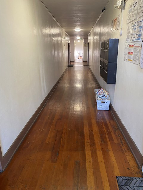 A long hallway with a wooden floor and white walls.