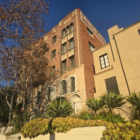 A tall red brick building with a balcony on the second floor.