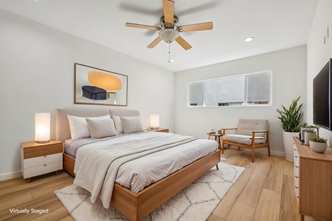 A bedroom with a bed, a chair, and a ceiling fan.