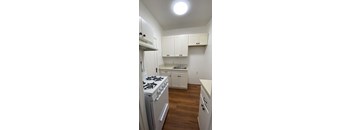 A small kitchen with a white stove and cabinets.